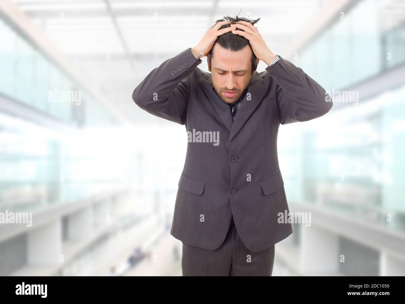 Businessman in a suit gestures with a headache, at the office Stock Photo