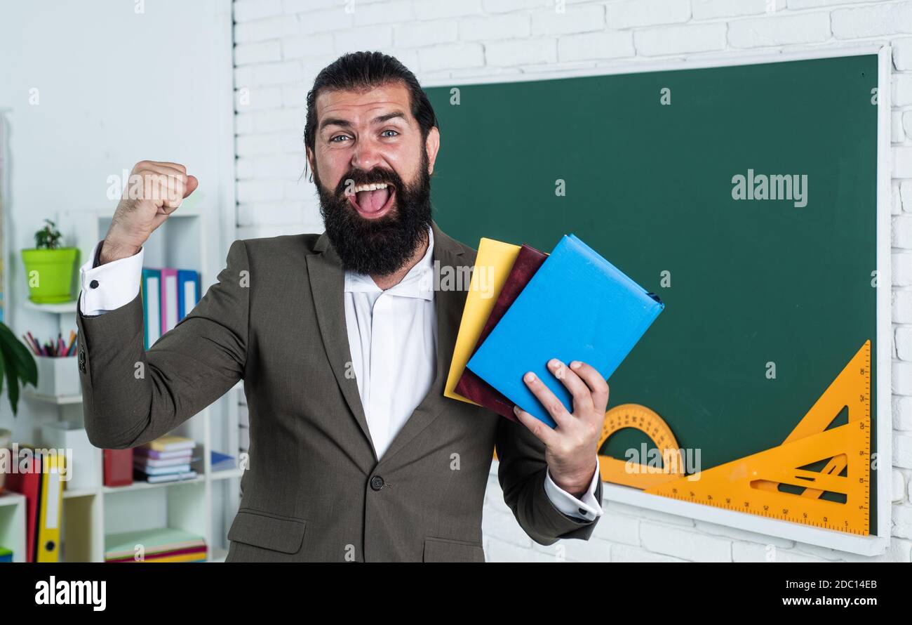 great day. learning the subject. happy man with beard holding book. literature for studying. informal education. male student in school classroom while lesson. pass the exam. Stock Photo