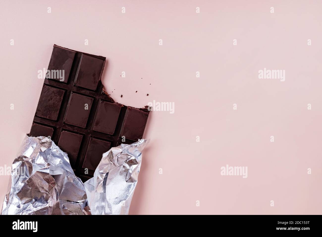 Bited bar of chocolate in foil with crumbs Stock Photo