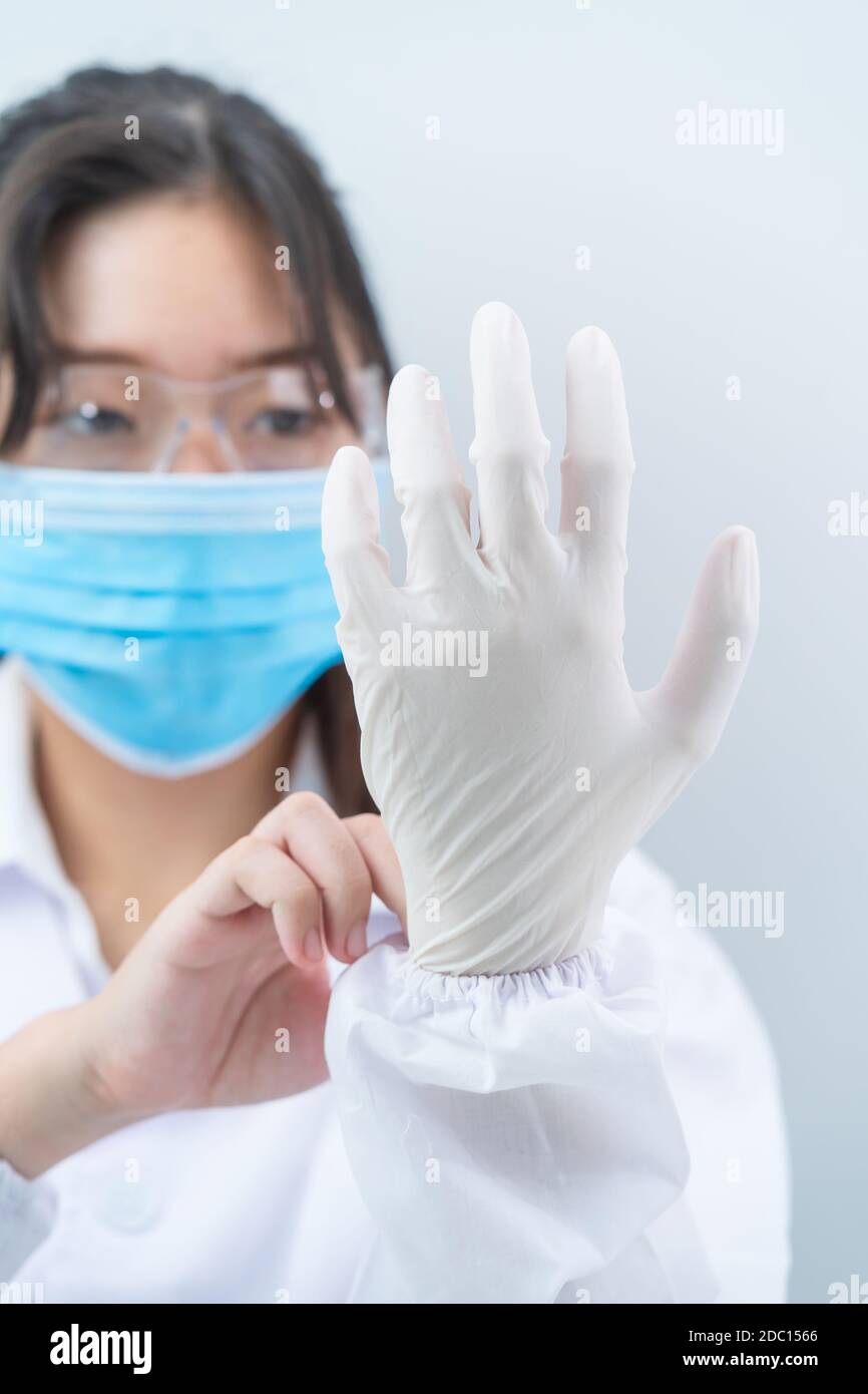 Close Up Scientist Hands Putting In Nitrile Gloves In Labcoat Wearing 