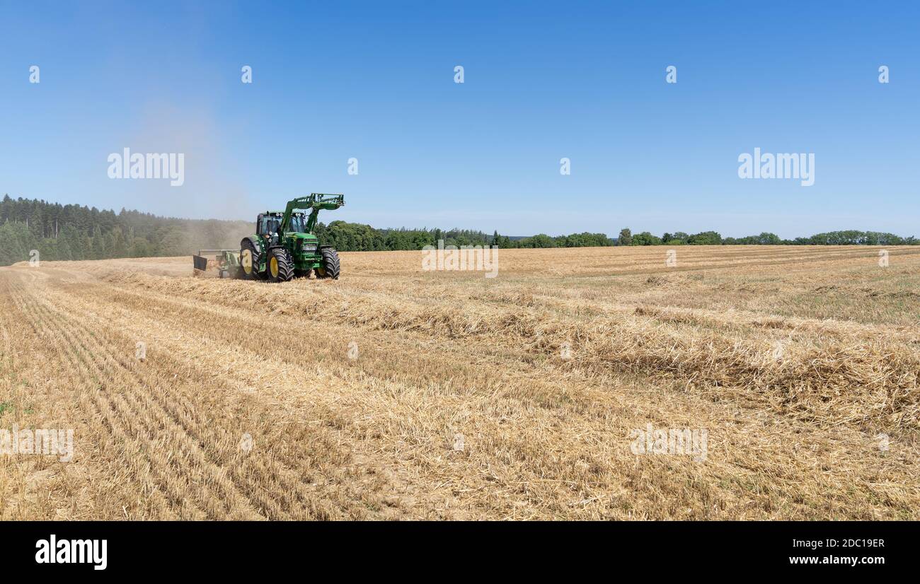 Tractor with hay rake on a stubble field Stock Photo