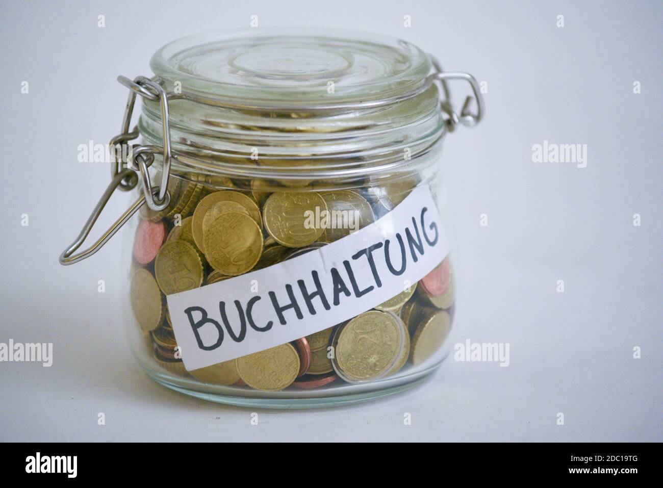 Jar full of coins with a label saying 'Buchhaltung' (accounting) Stock Photo