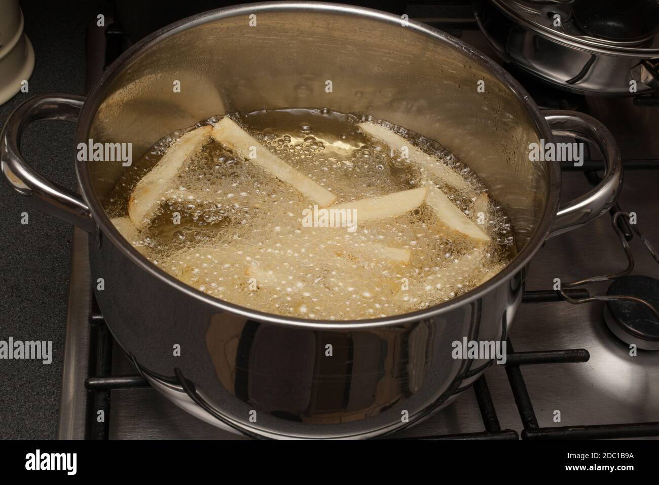 Homemade potato chips frying in a pan of hot oil Stock Photo