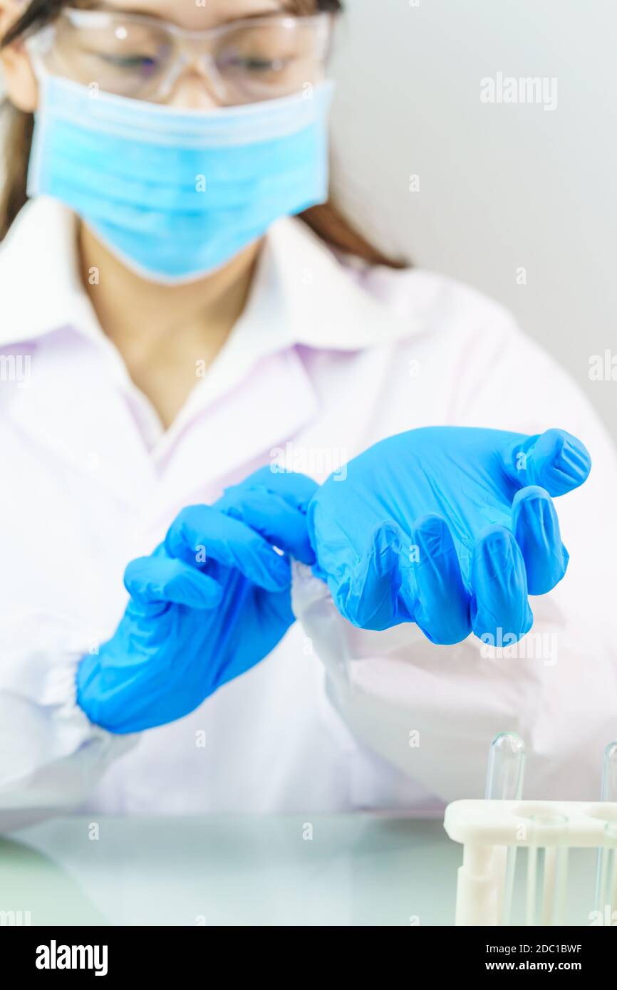 Close up Scientist hands putting in nitrile blue latex gloves in labcoat wearing nitrile gloves, doing experiments in lab Stock Photo