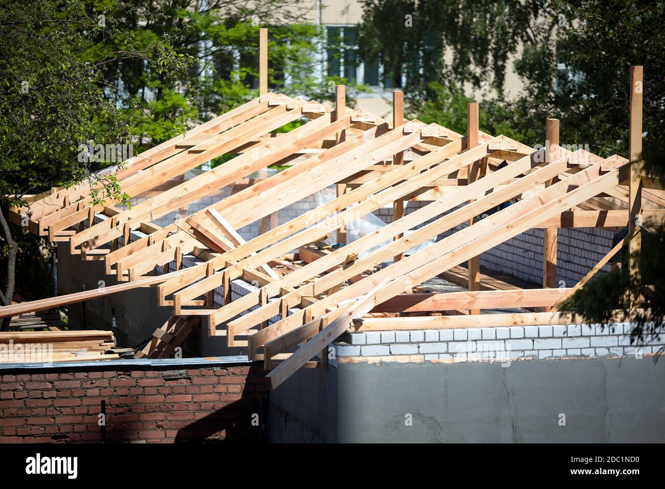 Roofing construction with wooden beams, logs, rafters, trusses. Roof  structure on top of brick walls with plaster surrounded by foliage on sunny  Stock Photo - Alamy