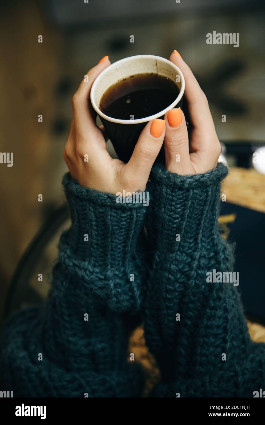 The human holds a cup of coffee with two hands in a warm autumn green ...