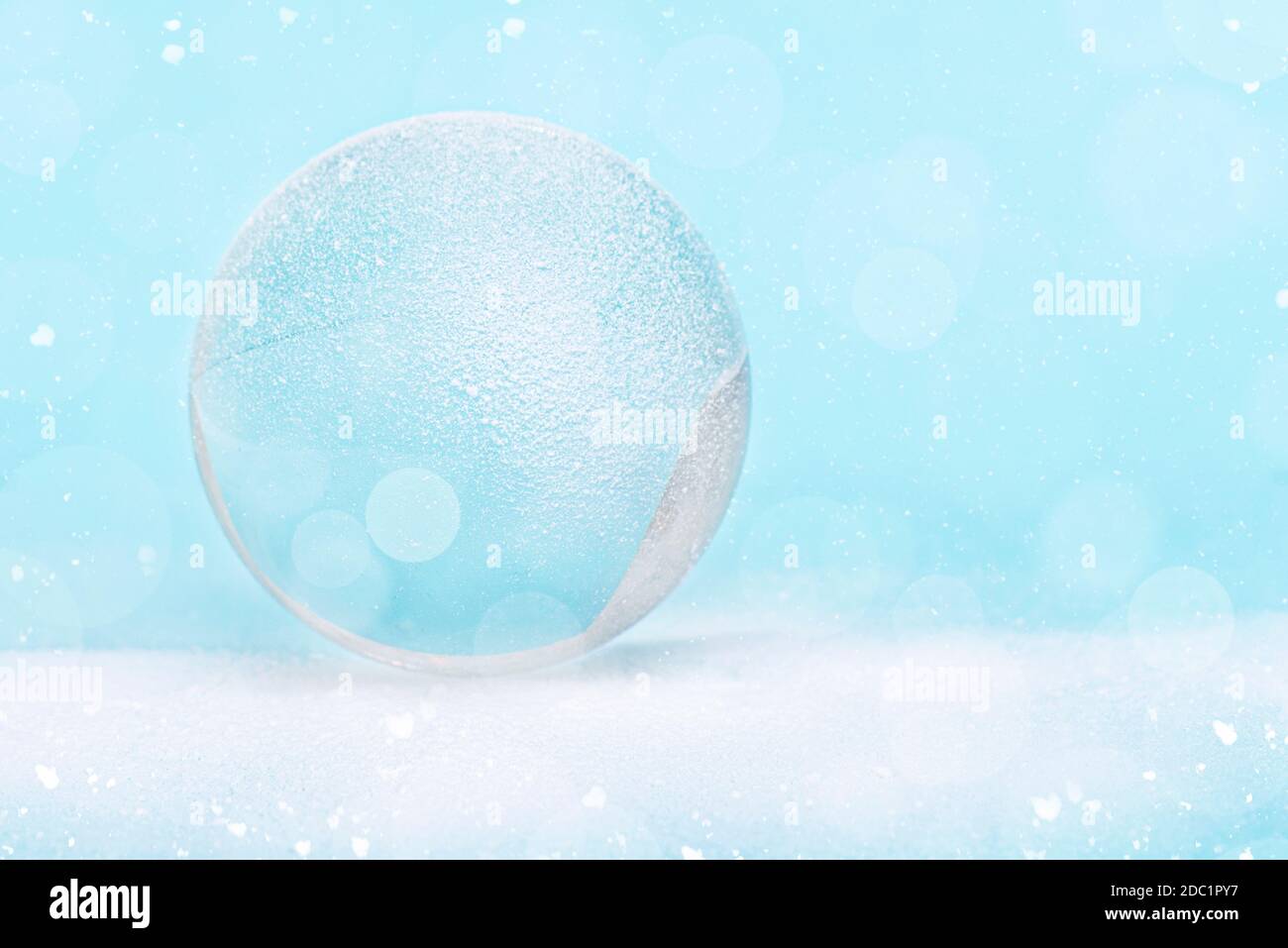 Snowglobe or glass ball covered by snow with glitter, Christmas decoration, layout, space for text, postcard. Stock Photo