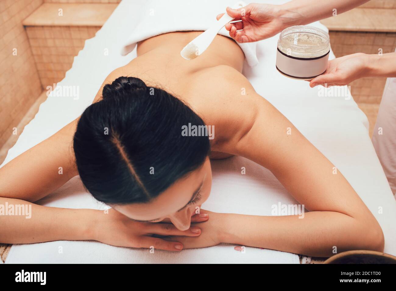 Brunette getting a salt scrub in the spa salon. Scrub cleanses and rejuvenates the skin Stock Photo