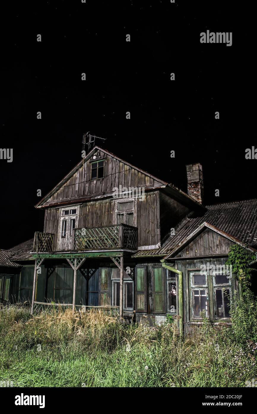 Old spooky abandoned wooden house illuminated on black night background Stock Photo