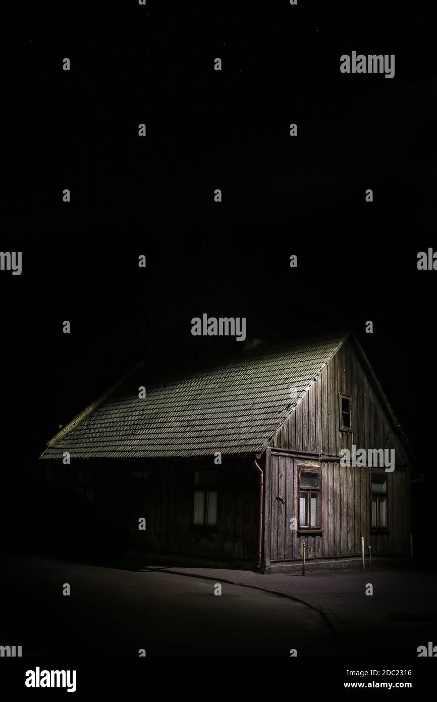 Old wooden house illuminated emerging from darkness of night Stock Photo