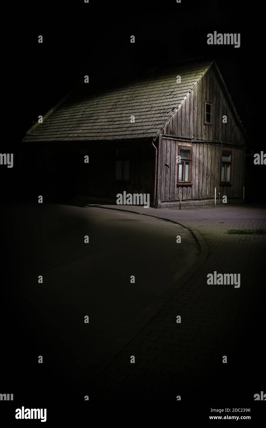 Old wooden house illuminated emerging from darkness of night Stock Photo