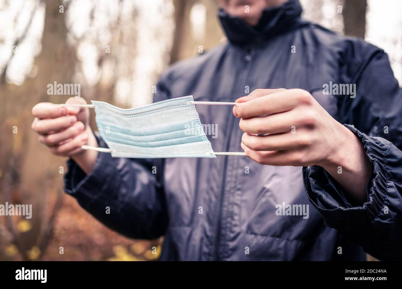 Man putting on a medical mask to protect from corona virus. Disposable facemask. Young person about to wear coronavirus protection. Covid-19 infection. Stock Photo