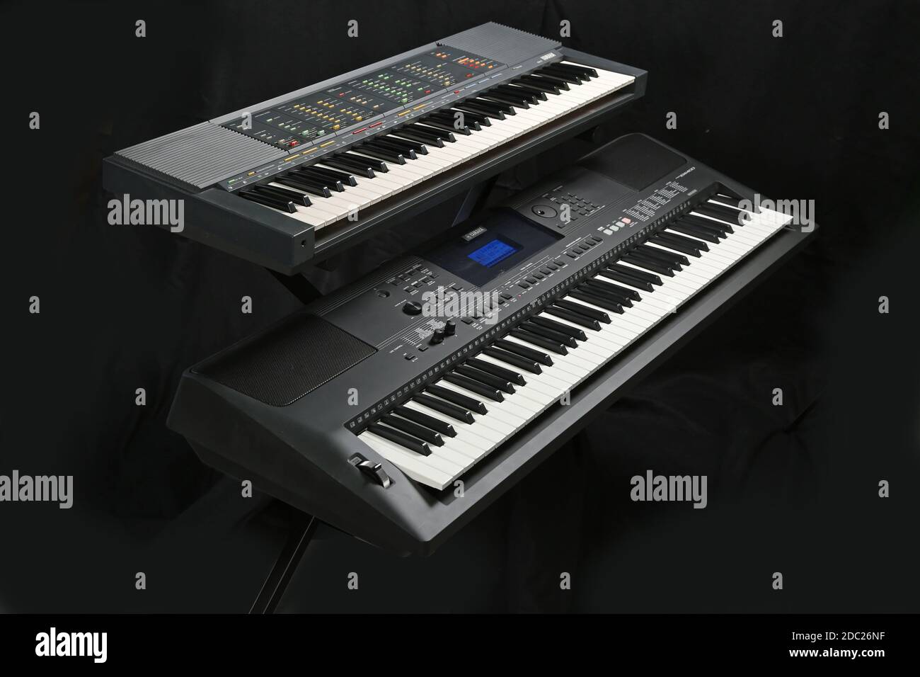 Studio shot of two Yamaha electronic keyboards; Model PSR 70 (top) and PSR EW400, on a folding, metal  X-frame stand. Stock Photo