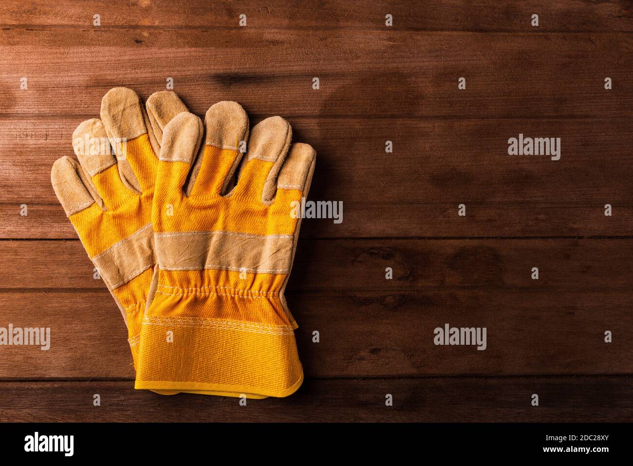 Close up of yellow safety protective gloves on wooden background Stock Photo