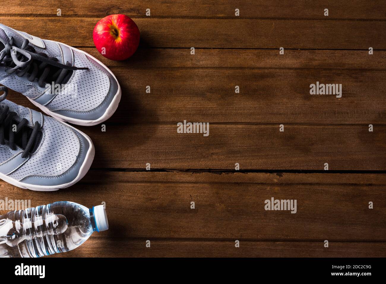 Top view of pair sports shoes, bottle water and red apple on wood table, Gray sneakers and accessories equipment in fitness GYM, Healthy workout conce Stock Photo