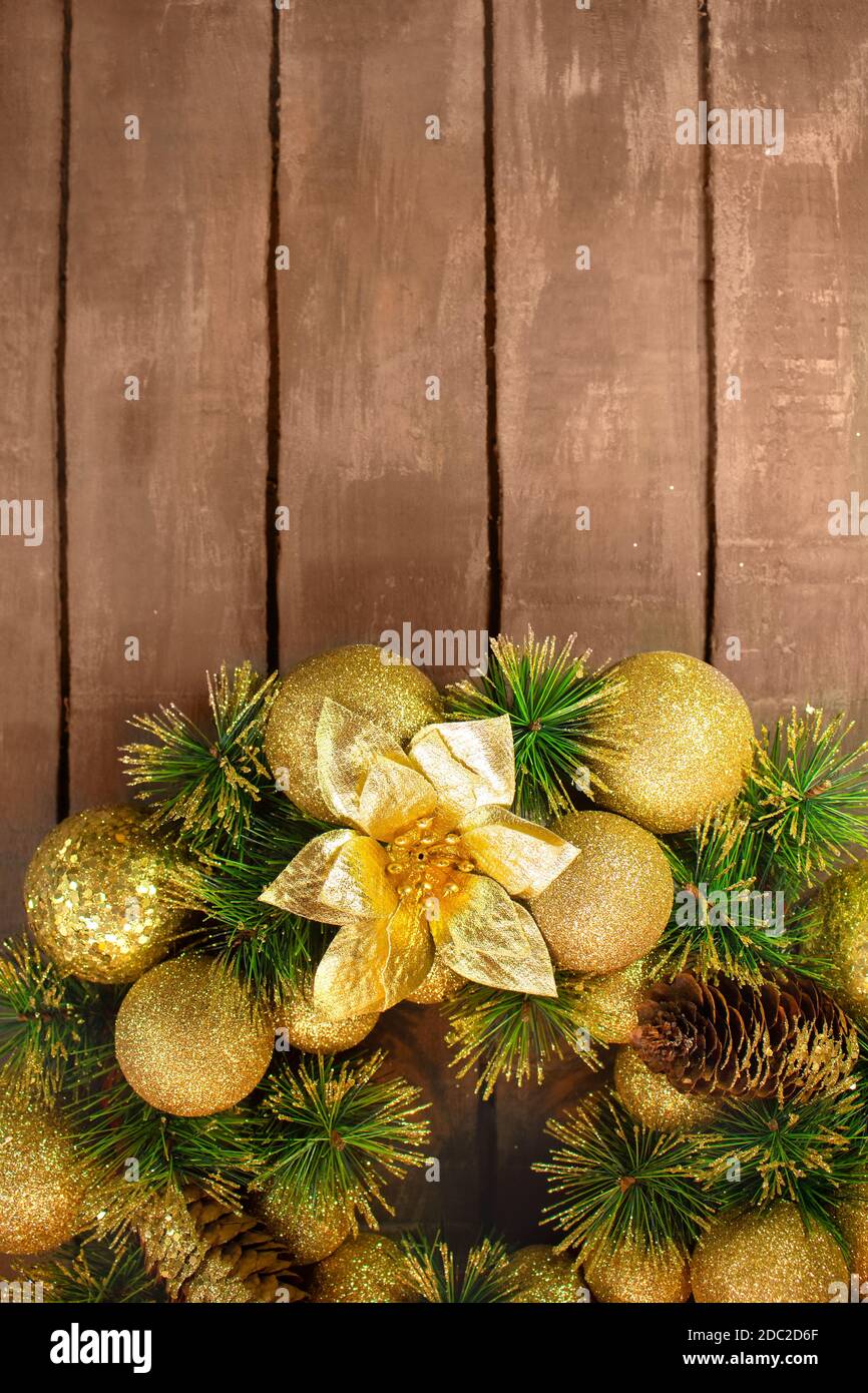 Shiny yellow Christmas balls and cone with barks and pine branches on brown wooden boards background. New year card Stock Photo