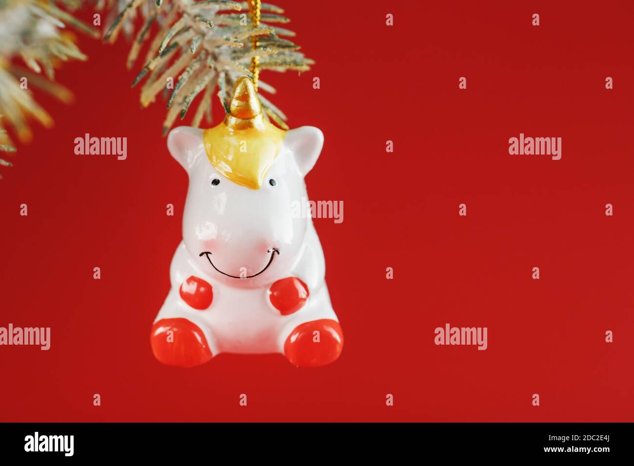 Unicorn figurine on a Christmas tree on a red background, free space