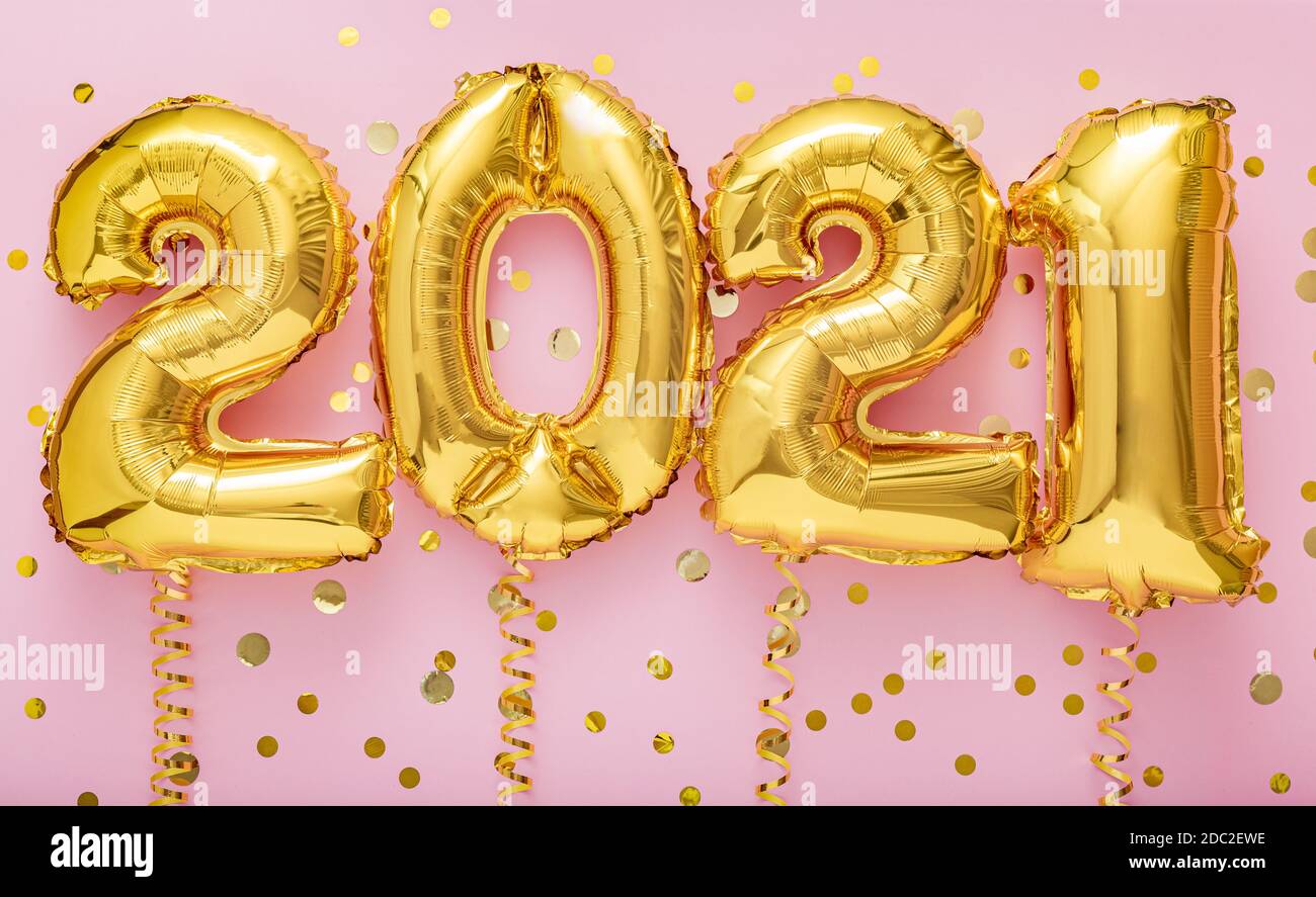 2021 year gold balloons on ribbons with confetti on pink wall. Happy New year 2021 eve celebration Stock Photo