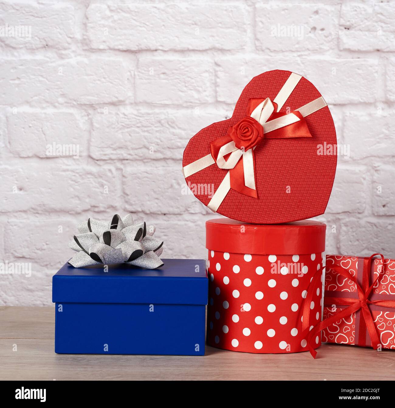 stack of various boxes with gifts on white brick background, festive backdrop Stock Photo