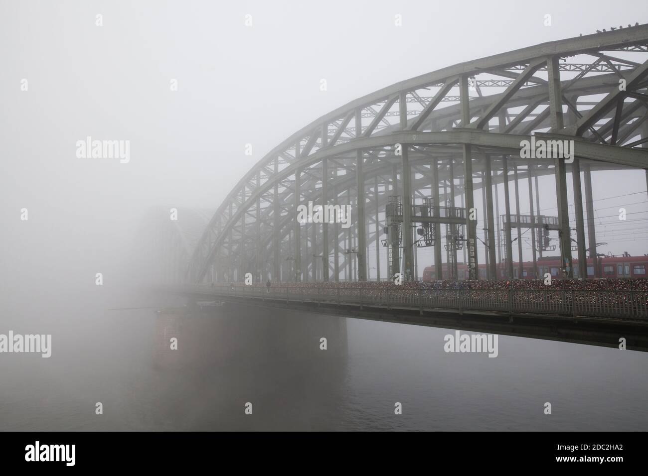 train on the Hohenzollern bridge over the river Rhine in the fog, Cologne, Germany.  Zug auf der Hohenzollernbruecke ueber den Rhein im Nebel, Koeln, Stock Photo