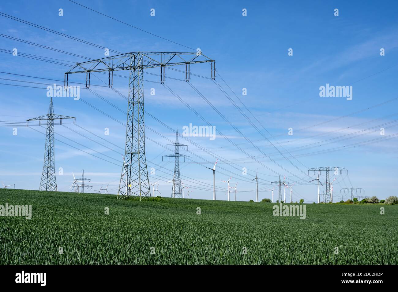 Power lines with wind turbines in the back seen in Germany Stock Photo