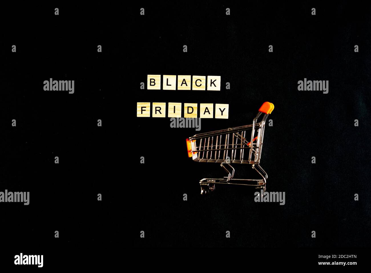 Black Friday written in wooden letters on a black background with a shopping basket, sales, holiday sales, top view, flat layout, price reduction Stock Photo