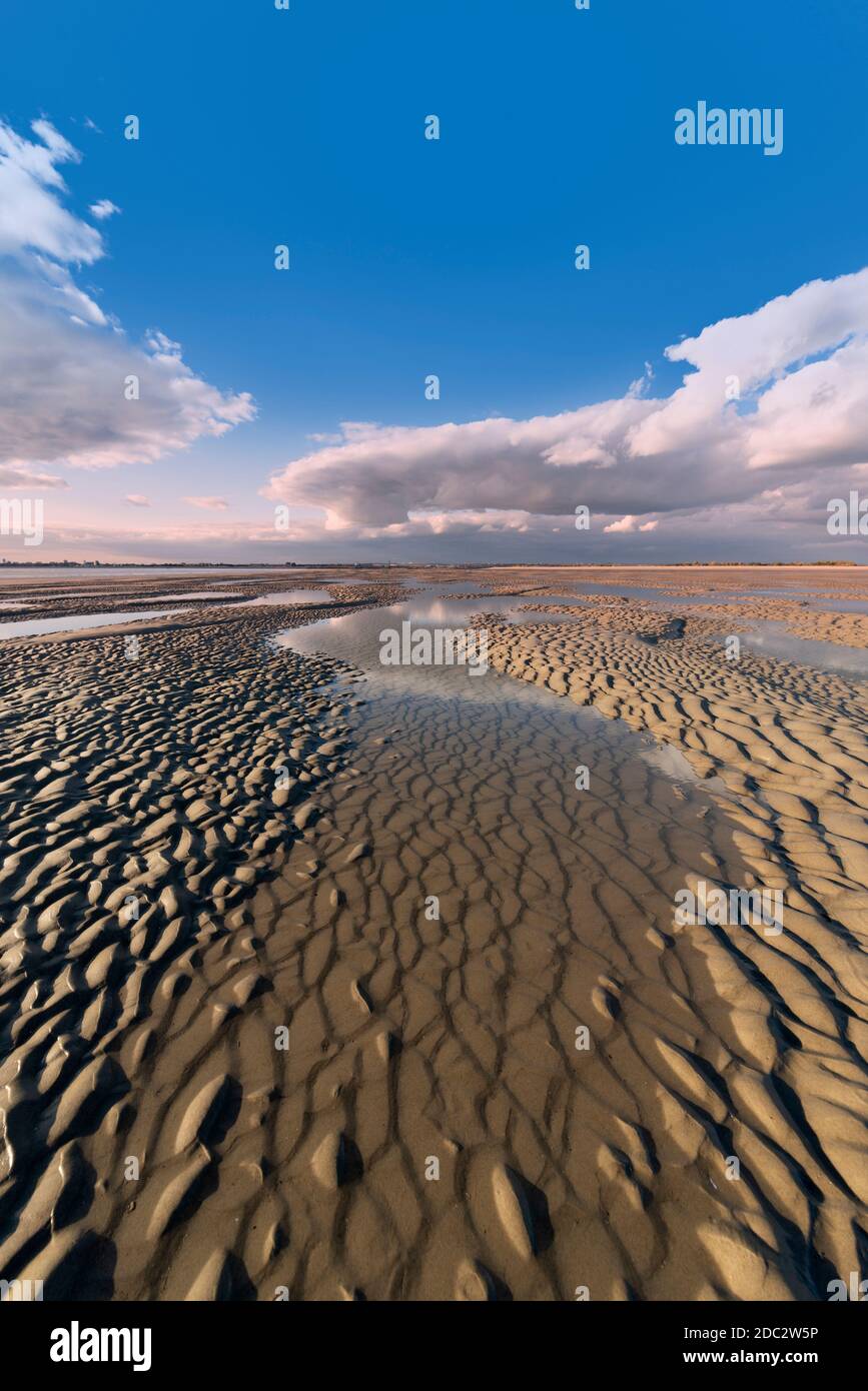 sandy beach at low tide with reflections of the sky, getting away from it all. Stock Photo