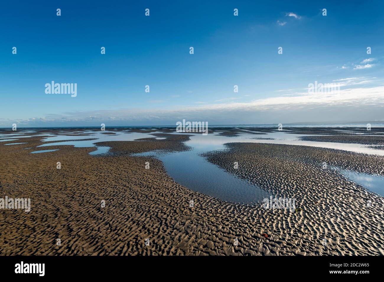 sandy beach at low tide with reflections of the sky, getting away from it all. Stock Photo
