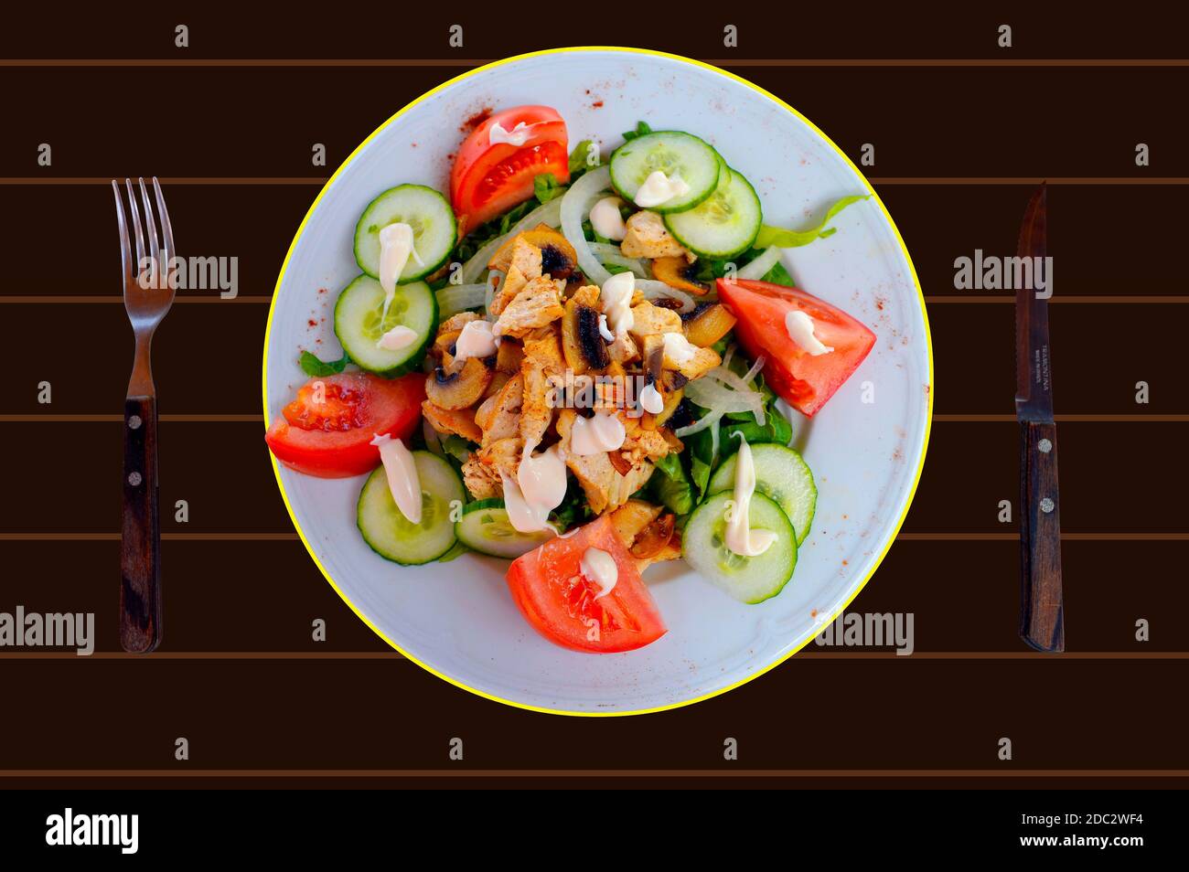 A plate of chicken and mushroom salad on a brown table Stock Photo