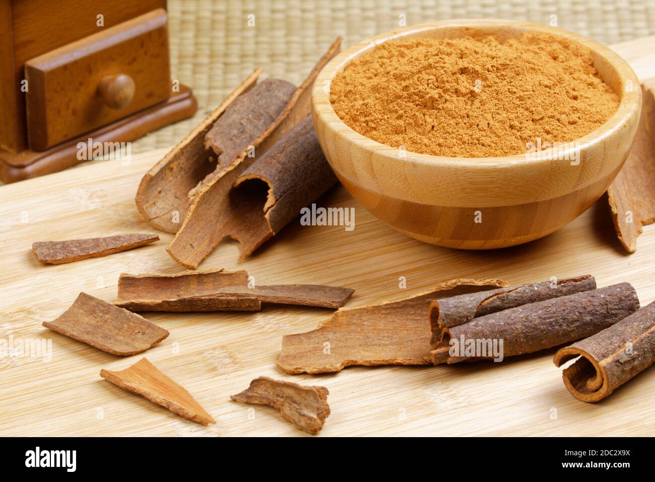 Wooden bowl of ground cinnamon and cinnamon bark on a wooden background Stock Photo