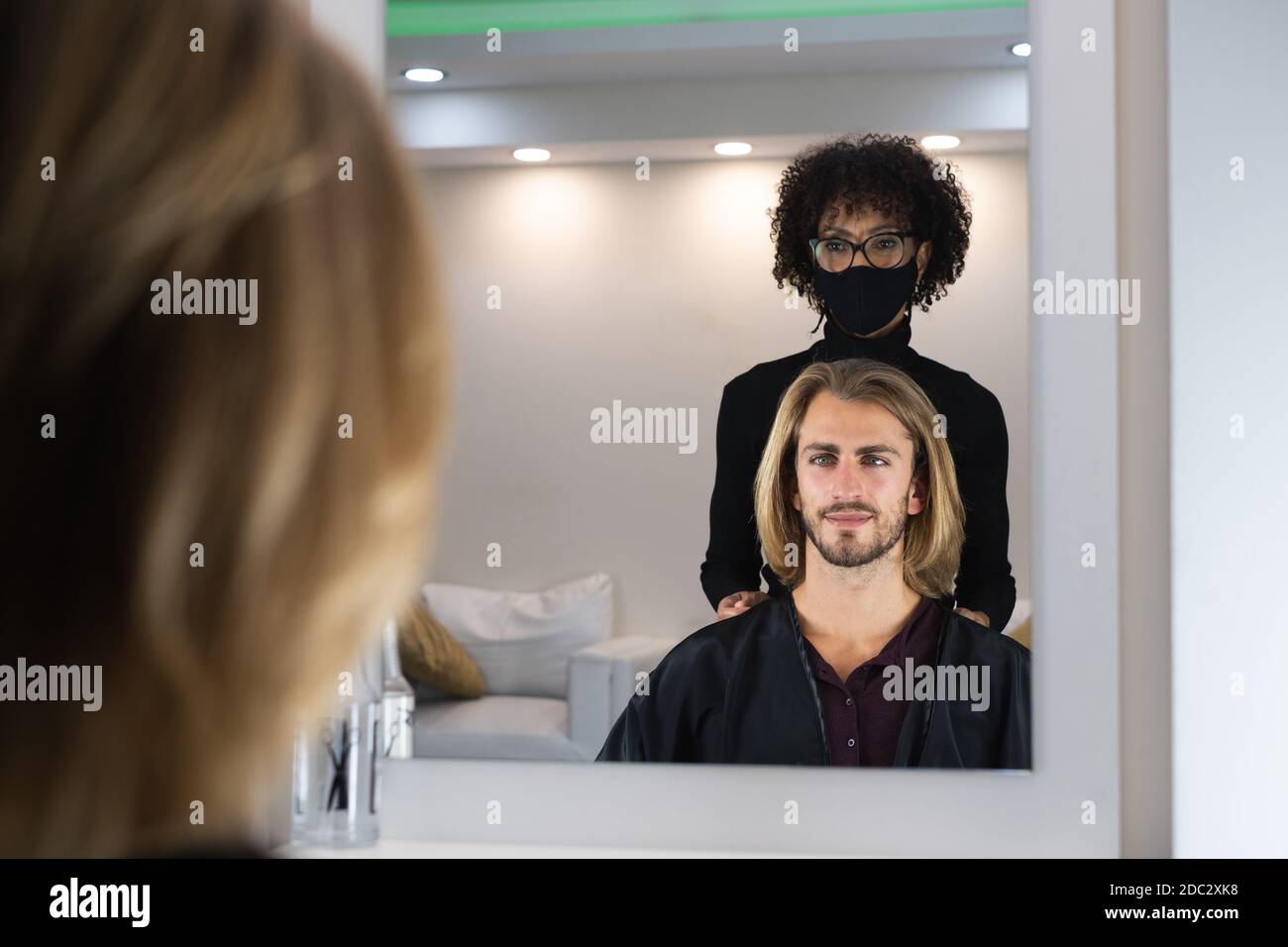 Handsome blonde male client getting haircut by black female hairdresser Stock Photo