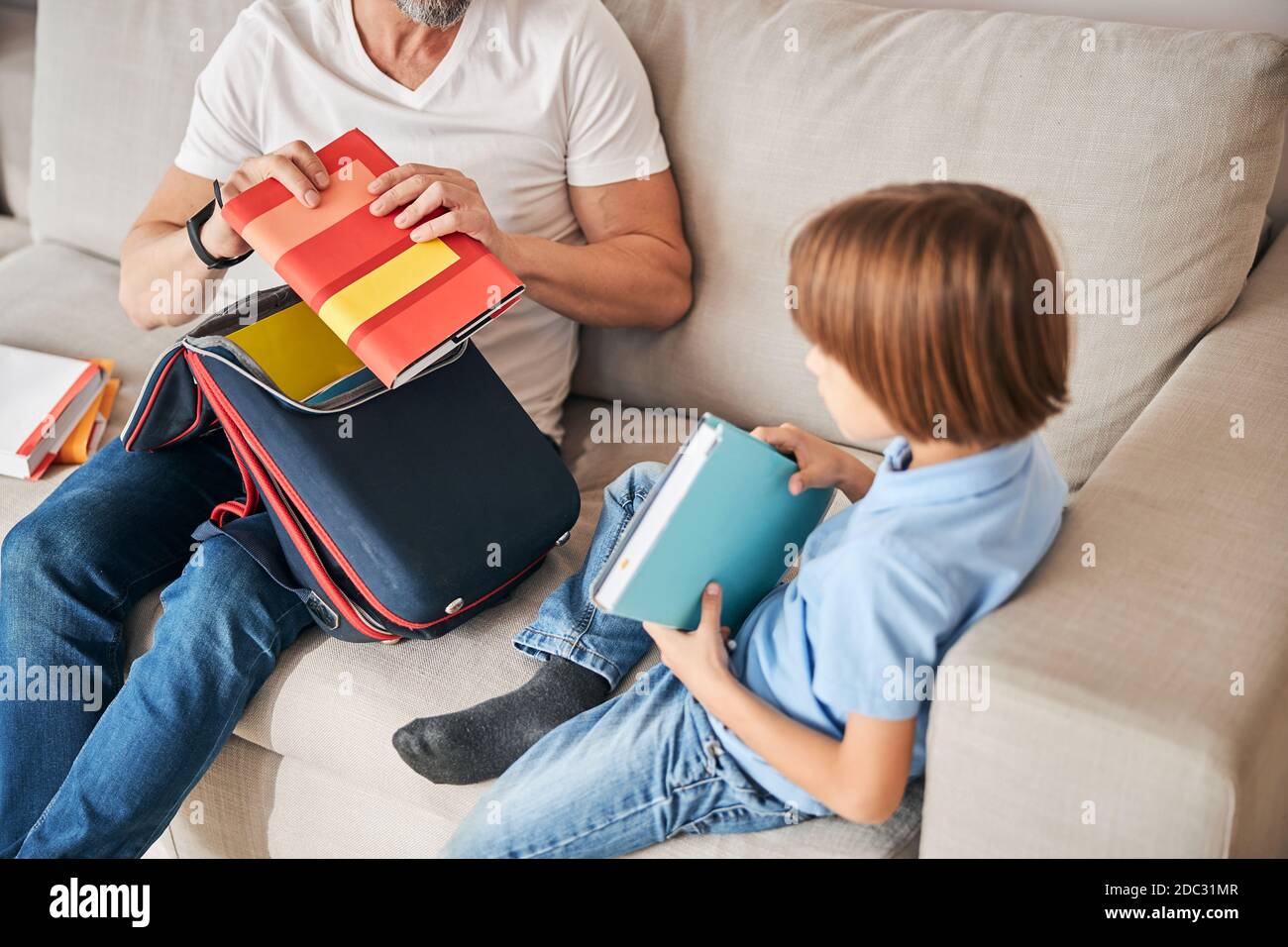 Little family of dad and kid unpacking a school-bag Stock Photo