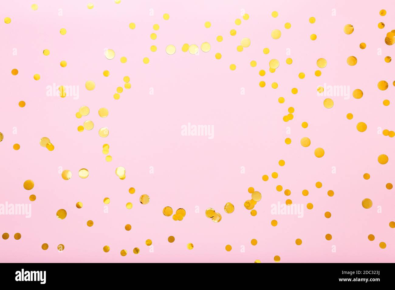 Gold confetti sparkles frame on pink background. Flat lay, top view festive backdrop with circle copy space. Celebration concept. Stock Photo
