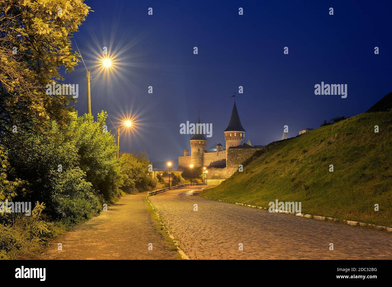 Night landscape with a road leading to the old fortress. Lamplight in the street. Historic Landmark. Old town of Kamenetz-Podolsk, Ukraine, Europe Stock Photo