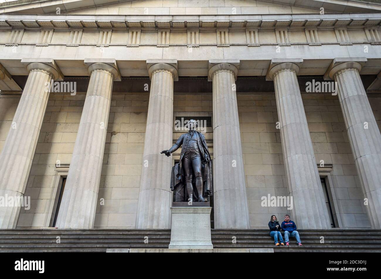 Couple Sitting in Front of Federal Building in Wall Street. Greek Style Building in Financial District, Manhattan, New York City, USA Stock Photo
