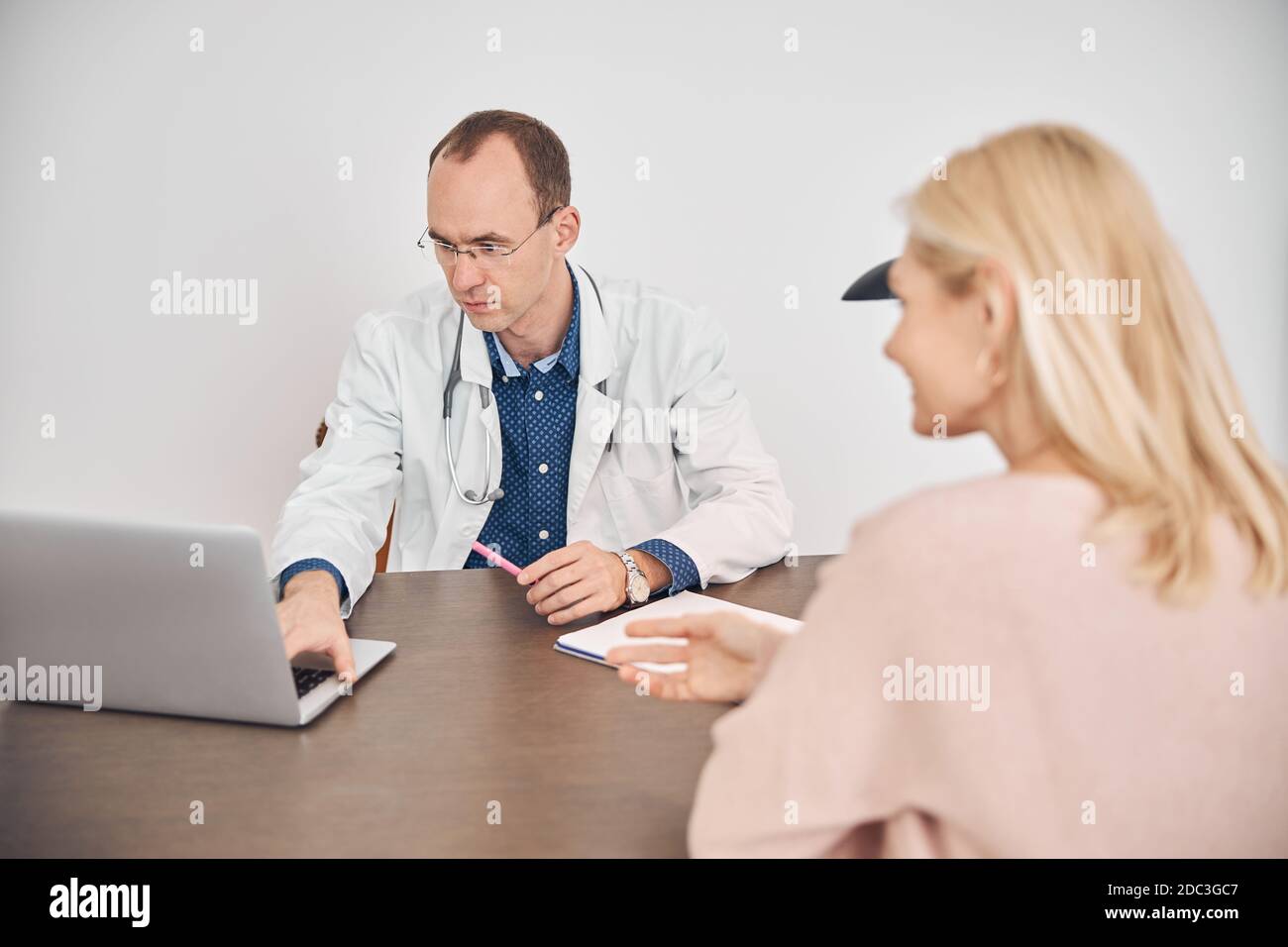 Blonde Caucasian woman consulting with the doctor Stock Photo - Alamy