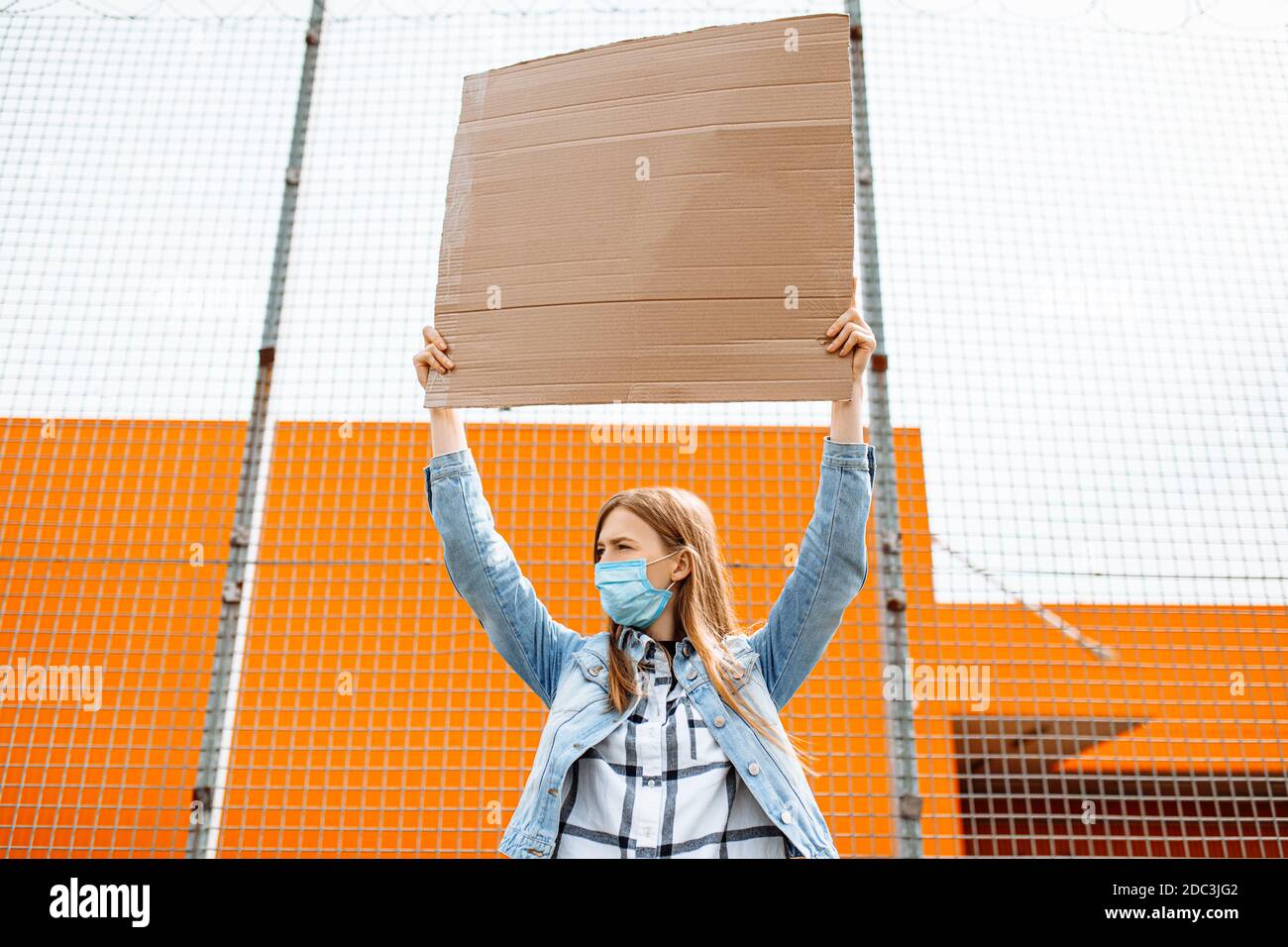 A young woman in a medical protective mask holds an empty cardboard ...