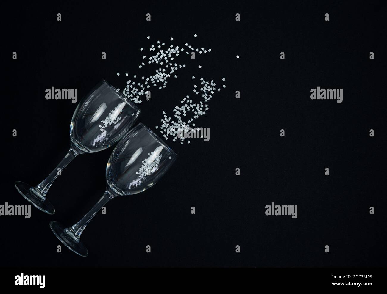 Wine glasses with silver confetti on a black background. Copy space. Stock Photo