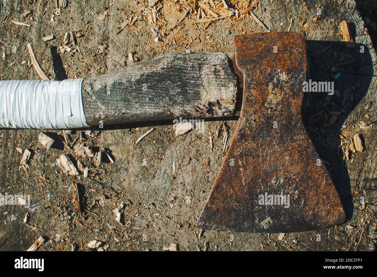 A vintage ax with a white handle laying on the stump Stock Photo