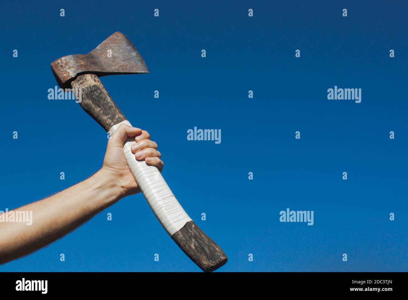 A European man hand tightens a white handle of an old ax with the sky on the background. Concept of strength, revolution and freedom Stock Photo