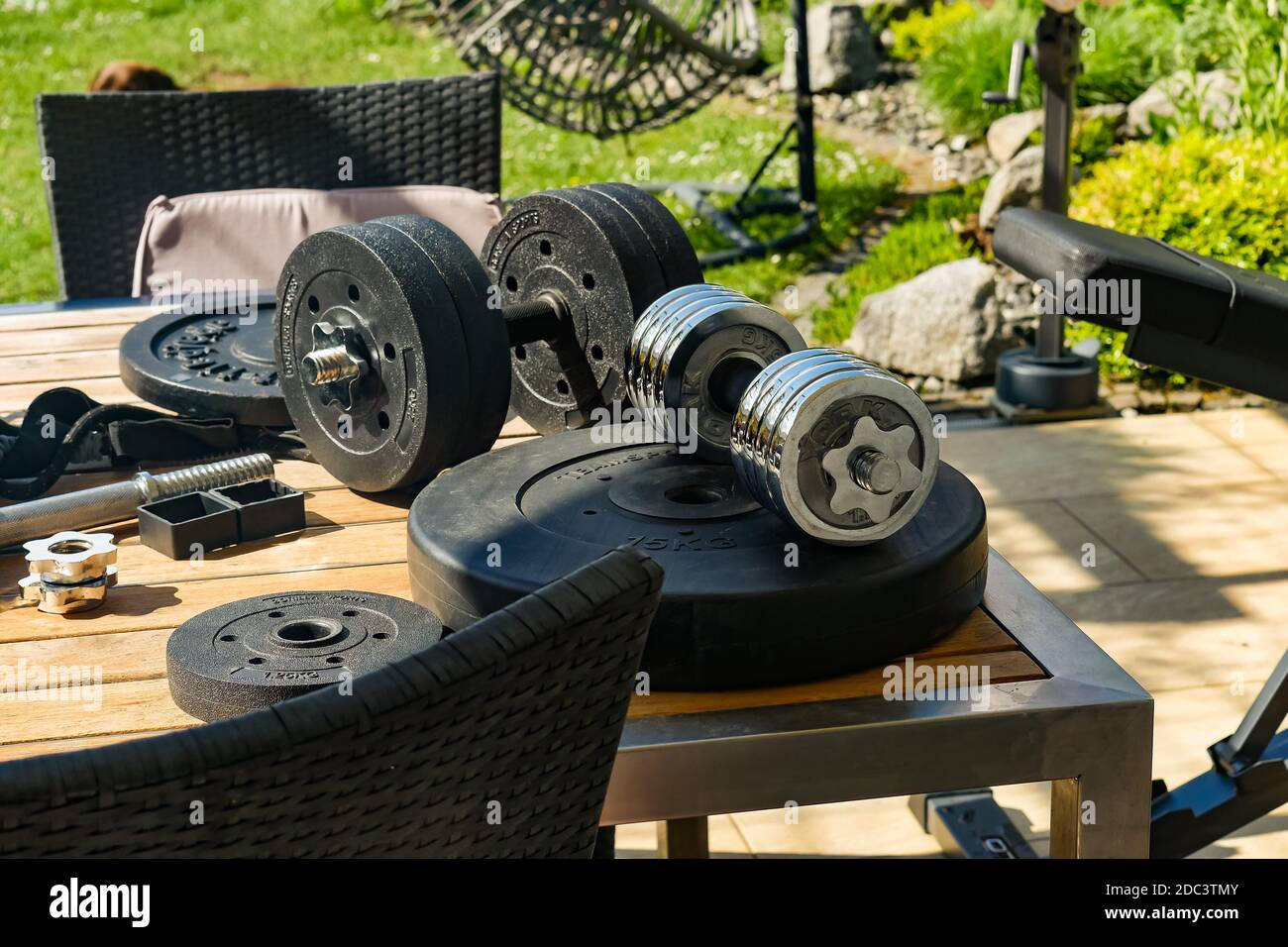 Exercise weights and adjustable dumbbells on outdoor table. High angle view. Stock Photo