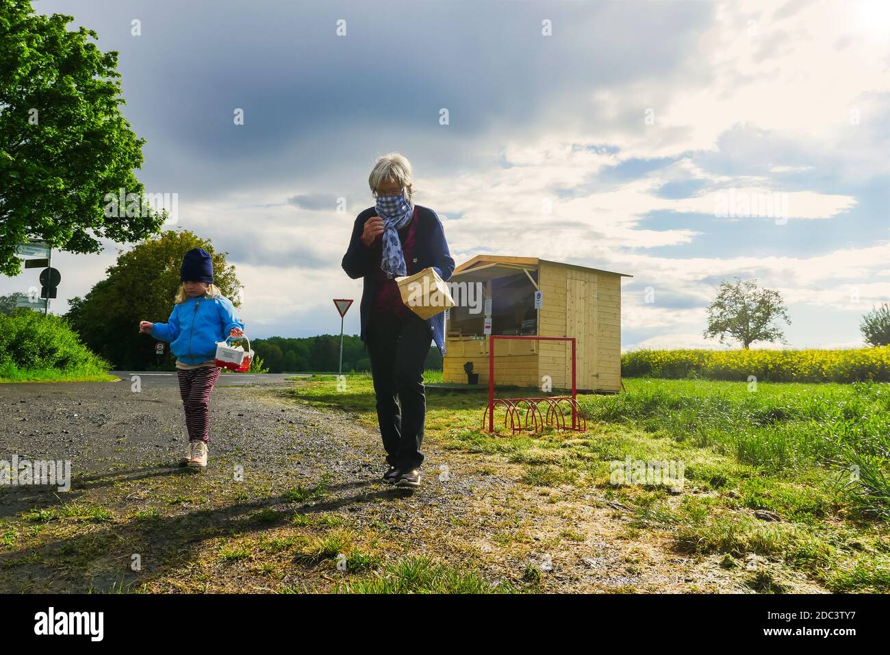 Child and grandmother walking on road in rural area. Long shot. Stock Photo