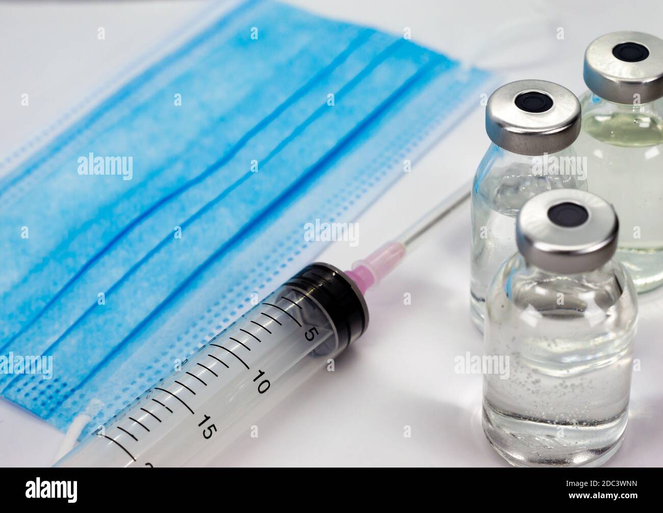 Vaccine Vial, Syringe and blue Medical Face Mask Stock Photo