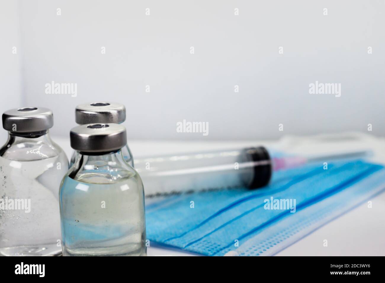 Vaccine Vial, Syringe and blue Medical Face Mask Stock Photo