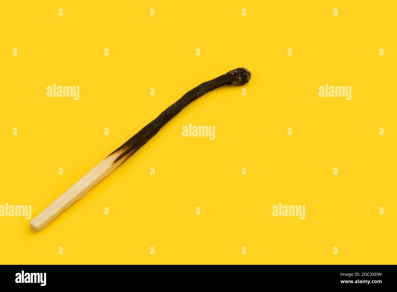 A burned macth on a yellow background with copy space Stock Photo