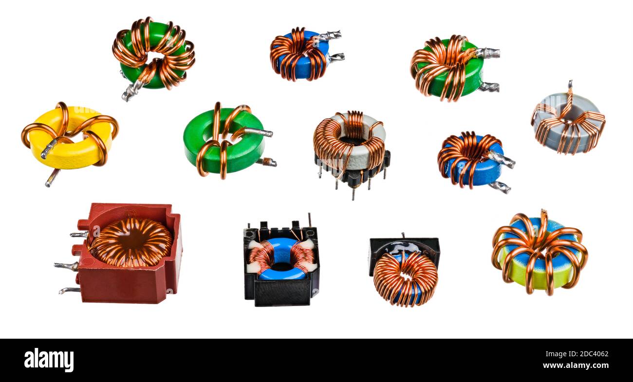 Various toroidal inductors or transformers. Collection of electronic induction coils with wrapped copper wire on ferromagnetic core. Electrotechnology. Stock Photo