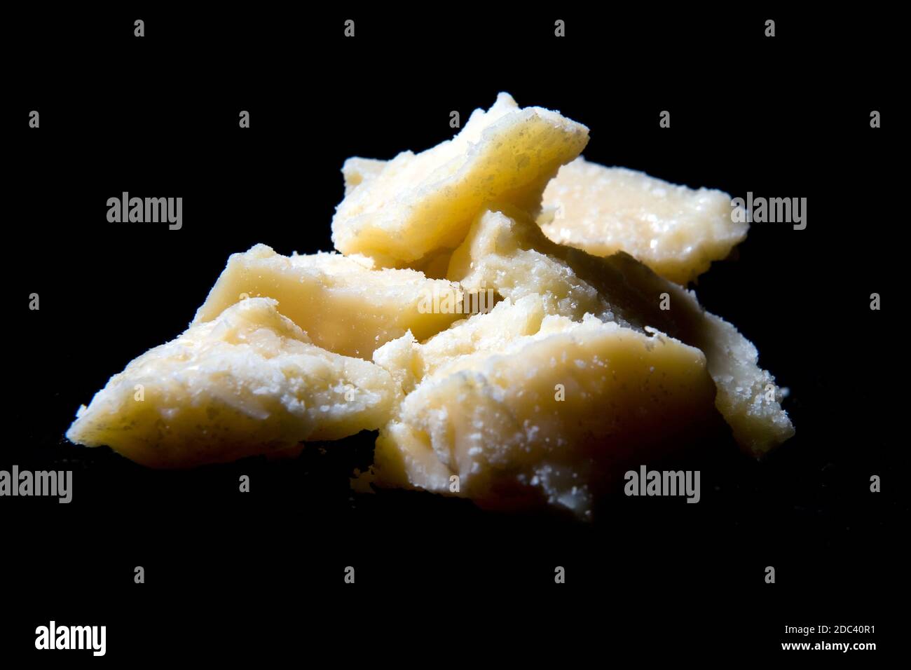 real Italian Parmiggiano Reggiano Parmesan cheese on a black background with cutting light Stock Photo
