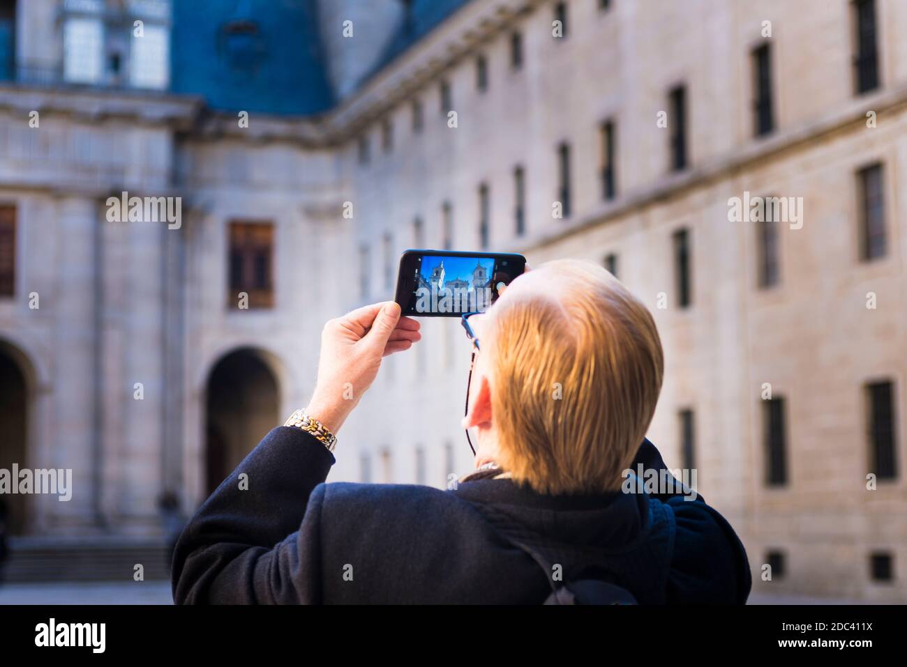 Tourist photographs the Courtyard of the Kings with his mobile phone. The Royal Site of San Lorenzo de El Escorial. San Lorenzo de El Escorial, Madrid Stock Photo