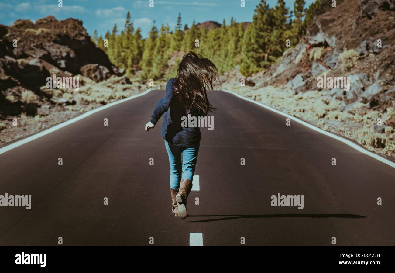 long haired young woman runs down the road feeling free and relaxed ...