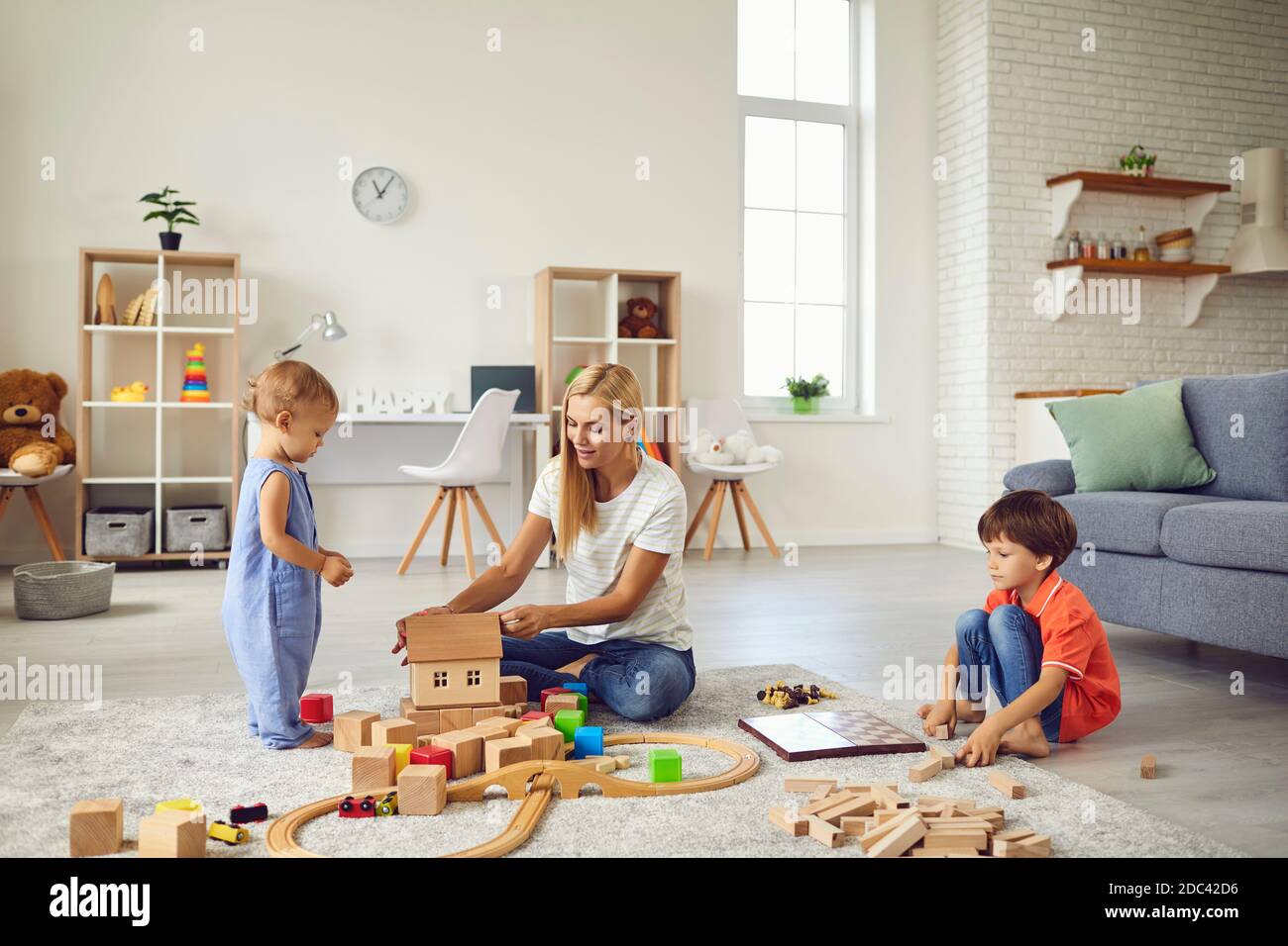 Mother playing educational games with smiling children on floor at home Stock Photo